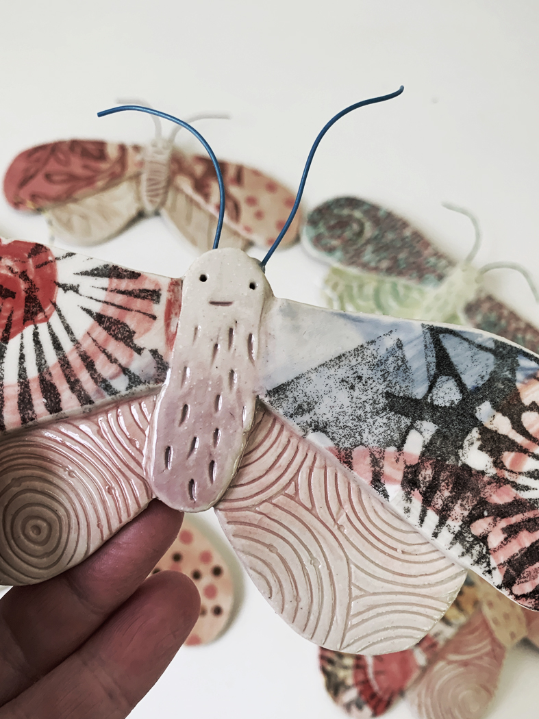 Ceramic moth sculpture with patterned wings held in a hand