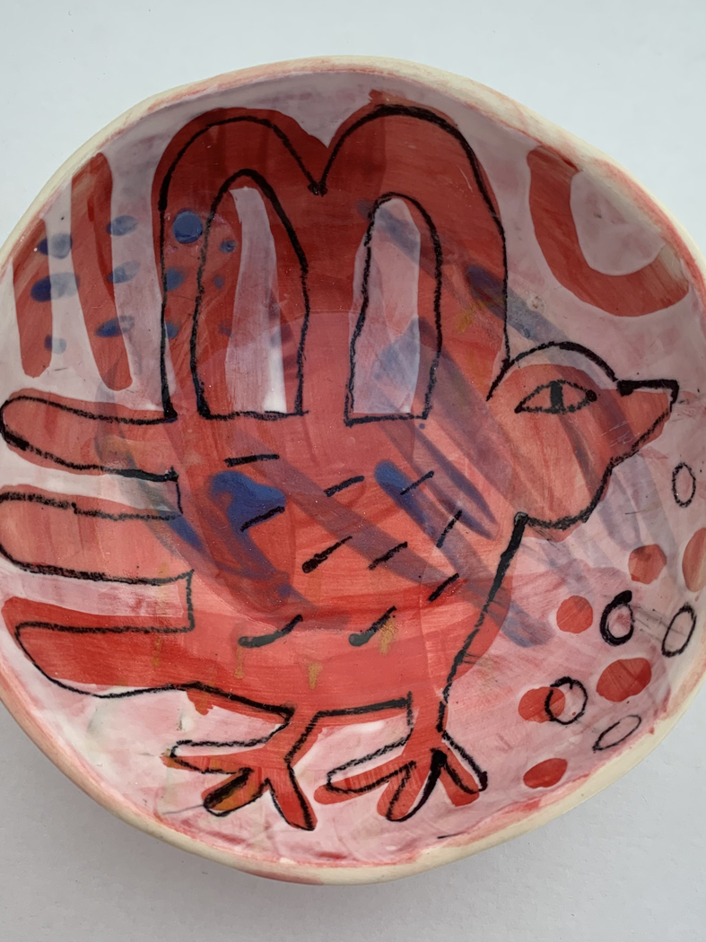 Circular ceramic bowl painted with a bold red bird motif